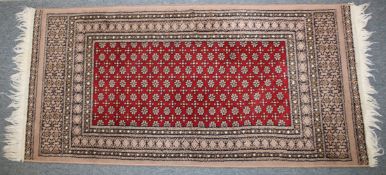 A PERSIAN RUG with stylised decoration on a red ground. 144cm x 66cm.