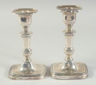 A PAIR OF SILVER CANDLESTICKS with rectangular loaded bases. 6.5ins high. Sheffield 1918. Maker: