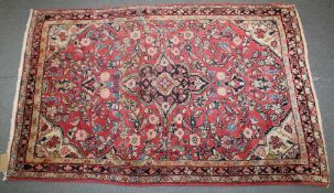 A PERSIAN RUG with floral design on a pink ground. 168cm x103cm.