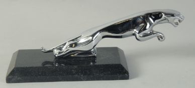 A JAGUAR CHROME MASCOT on a marble stand.