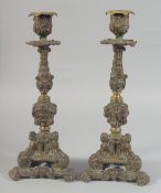 A GOOD PAIR OF BRONZE CANDLESTICKS with triangular cupid bases. 12ins high.