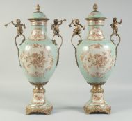 A PAIR OF PORCELAIN AND ORMOLU VASES AND COVERS painted with flowers with gilt cherub handles. 1ft