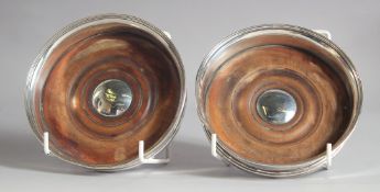 A PAIR OF PLAIN GEORGE III SILVER CIRCULAR WINE COASTERS with turned wood bases. 5.25ins diameter,