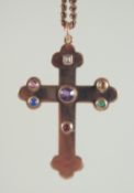 A 9CT GOLD CROSS on a chain, the cross inset with gemstones.