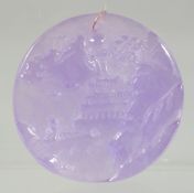 A GOLD RING ON A CIRCULAR JADE LILAC PENDANT. 2ins diameter.