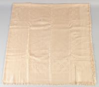 A LOUIS VUITTON CREAM SHAWL with Louis Vuitton emblems. 140cm x 120cm.