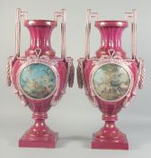A LARGE PAIR OF BURGUNDY SEVRES STYLE TWO HANDLED URNS with circular classical scenes. 1ft 11ins