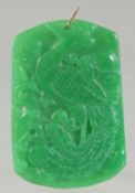 A GOLD RING ON A CARVED JADE PENDANT. 2.5ins x 1.5ins.