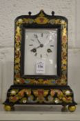 An ebonised mantle clock with brass inlaid decoration.