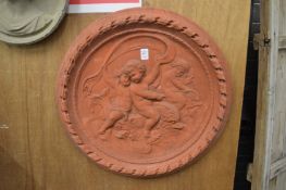 A large circular terracotta wall plaque moulded with cherubs.