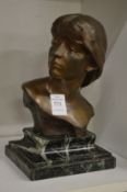 A bronze bust of a young girl on a marble base.
