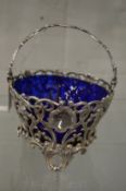 A good silver pierced swing handle basket with blue glass liner.