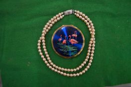 A string of pearls and a decorative compact.
