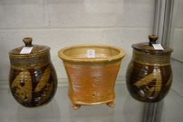 A salt glazed studio pottery jardiniere and a pair of treacle glazed pottery jars and covers.