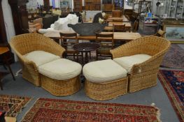 A pair of large wicker armchairs with matching foot stools.