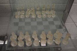 A glass chess board and various pieces (not a complete set).