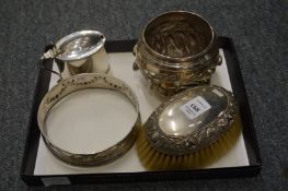 A silver oval mustard pot, lacking liner, an embossed silver bottle coaster frame, a silver backed