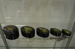 A graduated set of five Japanese oval lacquer boxes, each decorated with a mountainous landscape.
