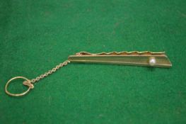 A gold and pearl tie clip.