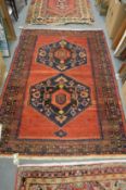 A Persian design rug, red ground with two large central medallions 158cm x 128cm.