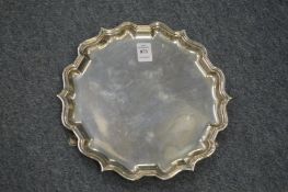 A silver salver with shaped border on three hoof feet.