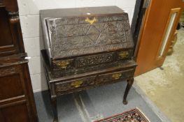 An 18th century carved oak bureau on stand.