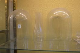 Two glass domes and two glass oil lamp chimneys.