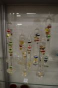A collection of colourful glass barometers/thermometers.