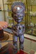 A large carved wood tribal figure of a standing female.