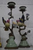 A pair of decorative pottery and brass candlesticks modelled as birds on branches.