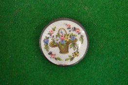 An enamelled silver circular pill box decorated with a basket of flowers (small rim damage).