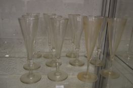 A set of ten cut glass champagne flutes together with a pair of etched champagne flutes.