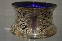 A silver dish ring embossed with running hounds and game, complete with blue glass liner.