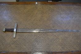 A sword with broad tapering triple fullered double edged blade, wire bound grip with plated brass