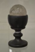 A crystal ball on turned wood stand.