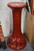 A Bretby red glazed pottery jardiniere stand.
