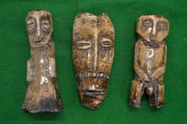 Three carved bone figures/masks.