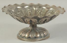 A 19TH CENTURY INDIAN EMBOSSED WHITE METAL TAZZA, with panels of deities, 23.5cm diameter.