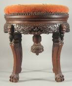 A LARGE CHINESE HARDWOOD STOOL, with upholstered seat, the skirt with relief faces, supported on