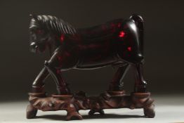 A RARE CHINESE BAKELITE -POSSIBLY CHERRY AMBER HORSE on original wooden stand, horse 21cm long,