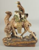 AN AMPHORA PORCELAIN GROUP OF A CAMEL AND RIDER, the camel being attacked by a lion, 38.5cm high.