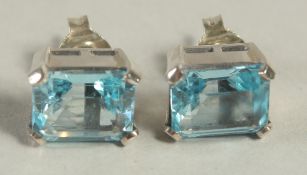 A PAIR OF BLUE TOPAZ AND SILVER EAR STUDS.