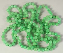 A VERY LONG STRING OF JADE BEADS with gold clasp. 60ins long.