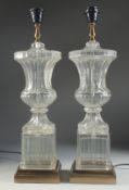 A GOOD PAIR OF GLASS URN SHAPED PEDESTAL LAMPS on a marble base. 23ins high.