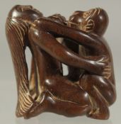 A CHINESE CARVED WOOD EROTIC NETSUKE. Signed.