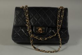 A SMALL CHANEL PADDED BLACK LEATHER BAG, 7.5ins long with entwined gilt and leather strap, 14ins