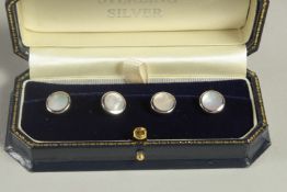 A SET OF FOUR STERLING SILVER AND MOTHER OF PEARL DRESS STUDS.