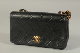 A CHANEL BLACK PADDED LEATHER SHOULDER BAG with long gilt metal and leather entwined strap. 20ins
