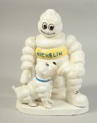 A WHITE CAST IRON MICHELIN MAN with a dog on a shaped base. 8ins high.