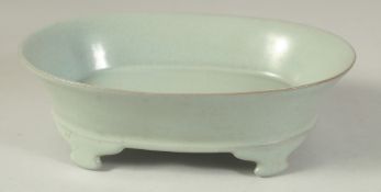A CHINESE CELADON GLAZE OVAL FROM BRUSH WASHER raised on four feet. 19cm long.